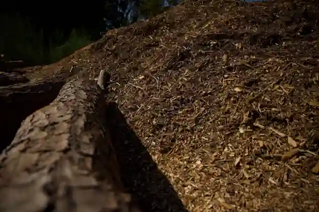 A mound of organic hardwood mulch with a bark-covered log in front of it
