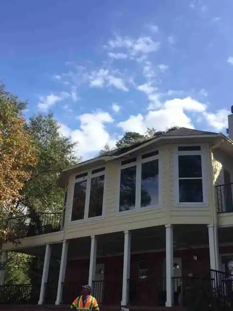 The same two-storey porch house cleared of the fallen pine, one crew member on the lawn